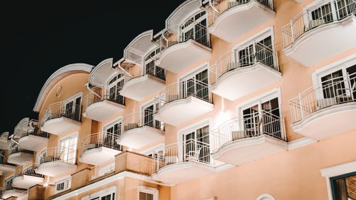 Free Low angle view of a modern building with balconies lit at night, showcasing architectural elegance. Stock Photo