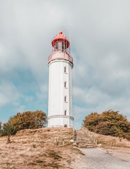 Picturesque lighthouse tower standing tall with a blue sky background, perfect for travel themes.