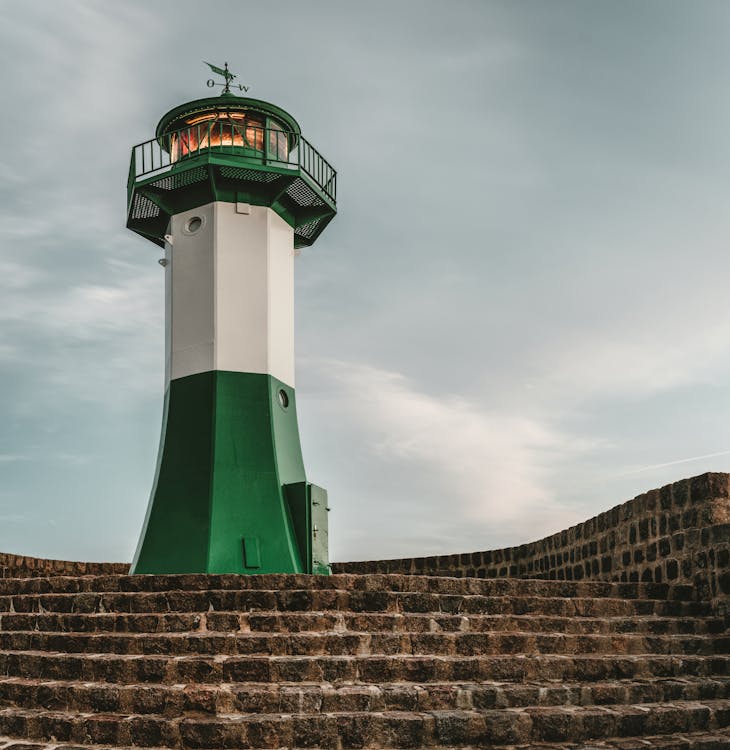 White and Green Lighthouse Under Gray Clouds