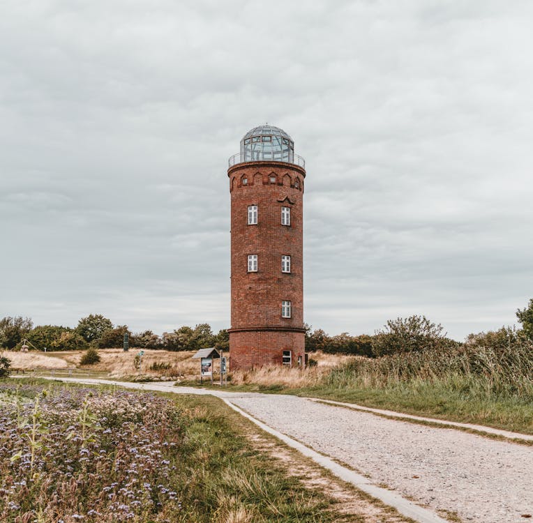 Round Brown Lighthouse Near Road Under White Cloudy Skies