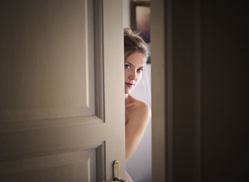 Free A woman peeks through a slightly opened door, creating a mysterious and intriguing atmosphere. Stock Photo