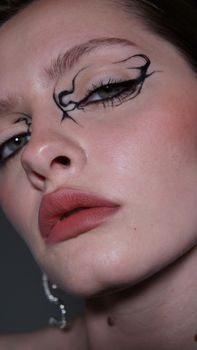 Elegant close-up of a woman with unique artistic eye makeup and red lipstick.