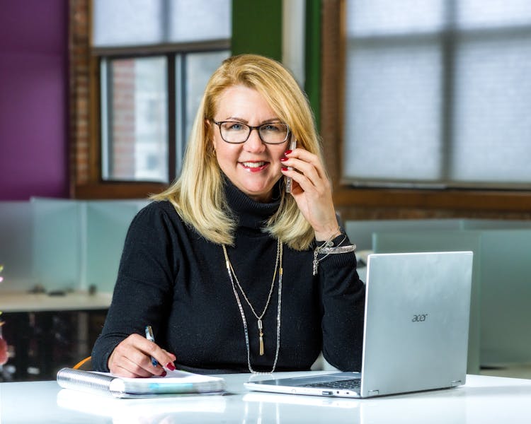 Woman At The Desk Using A Laptop And Phone 