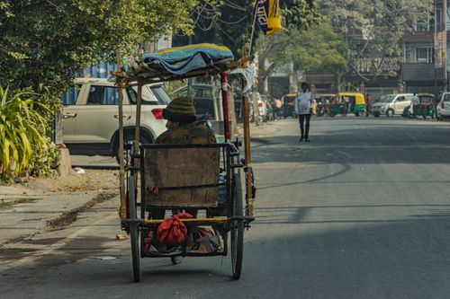 Free A senior man rides a rickshaw on a quiet city street, showcasing urban life. Stock Photo