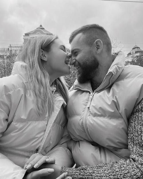 A Grayscale of a Couple Wearing Puffer Jackets