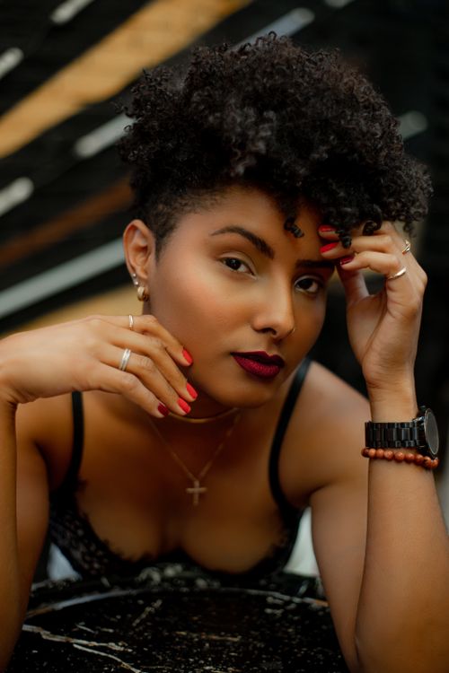 Free A striking portrait of a woman with black curly hair and bold makeup, showcasing elegance. Stock Photo