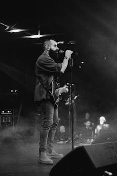 Monochrome shot of a male singer with an electric guitar, performing live on stage.