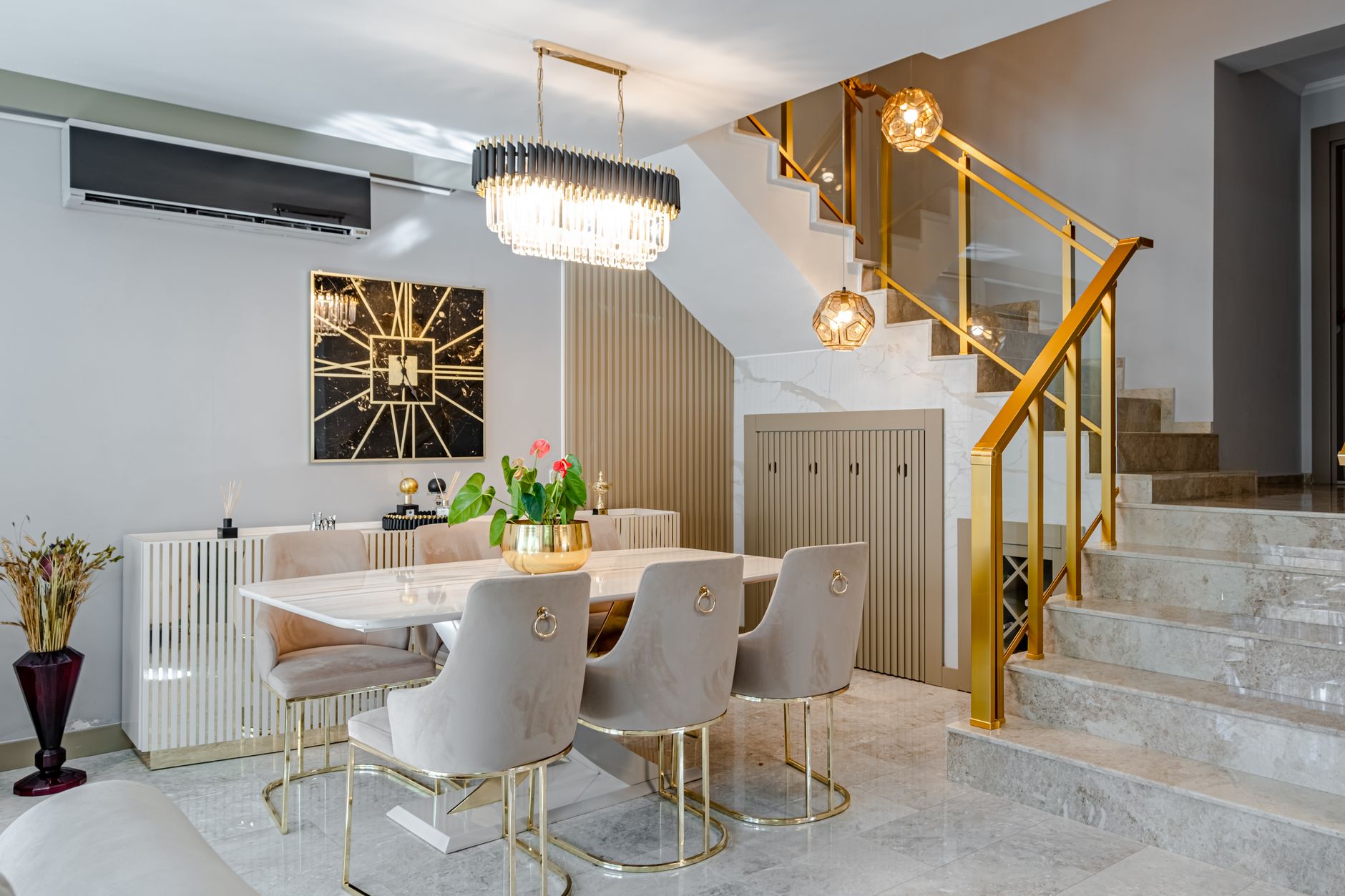 Modern dining room with marble table, gold accents, and stylish lighting.