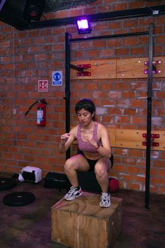 Young woman doing box jumps in an indoor gym wearing sportswear.
