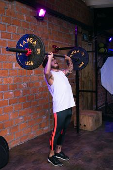 A determined man lifting heavy weights in an urban gym, showcasing strength and fitness.