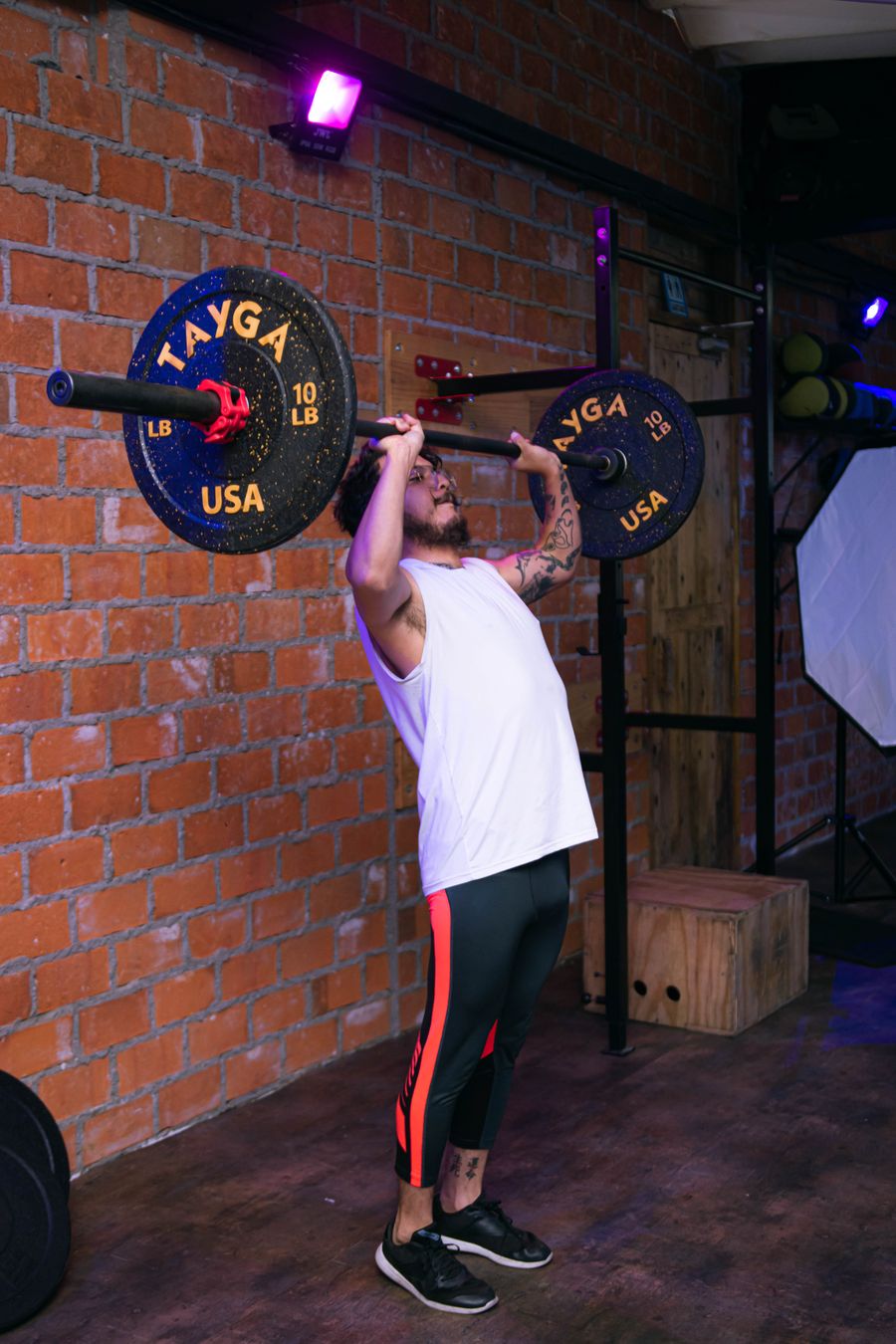 Man lifting heavy weights in an urban gym with brick walls