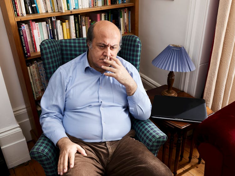 Man Sitting In Armchair In Home Library