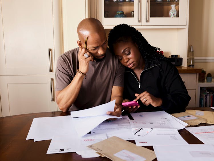 Couple Sitting By Table Calculating Expenses