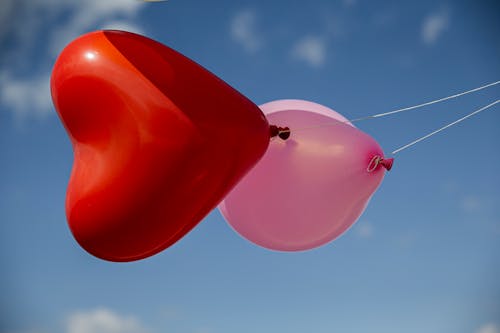 A Heart Shaped Balloon Beside a Pink Balloon