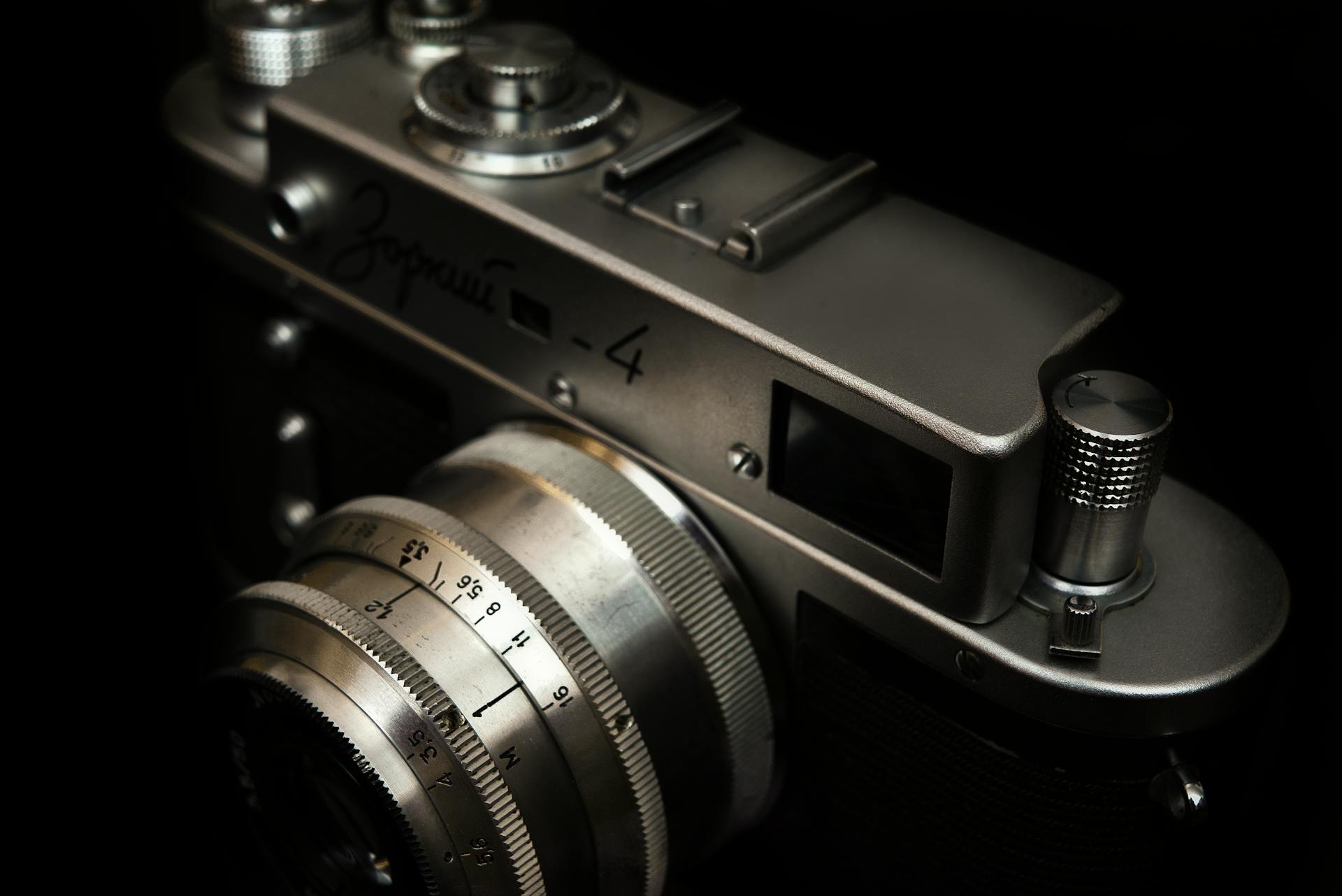 Detailed view of a classic film camera showcasing its chrome details against a dark backdrop.