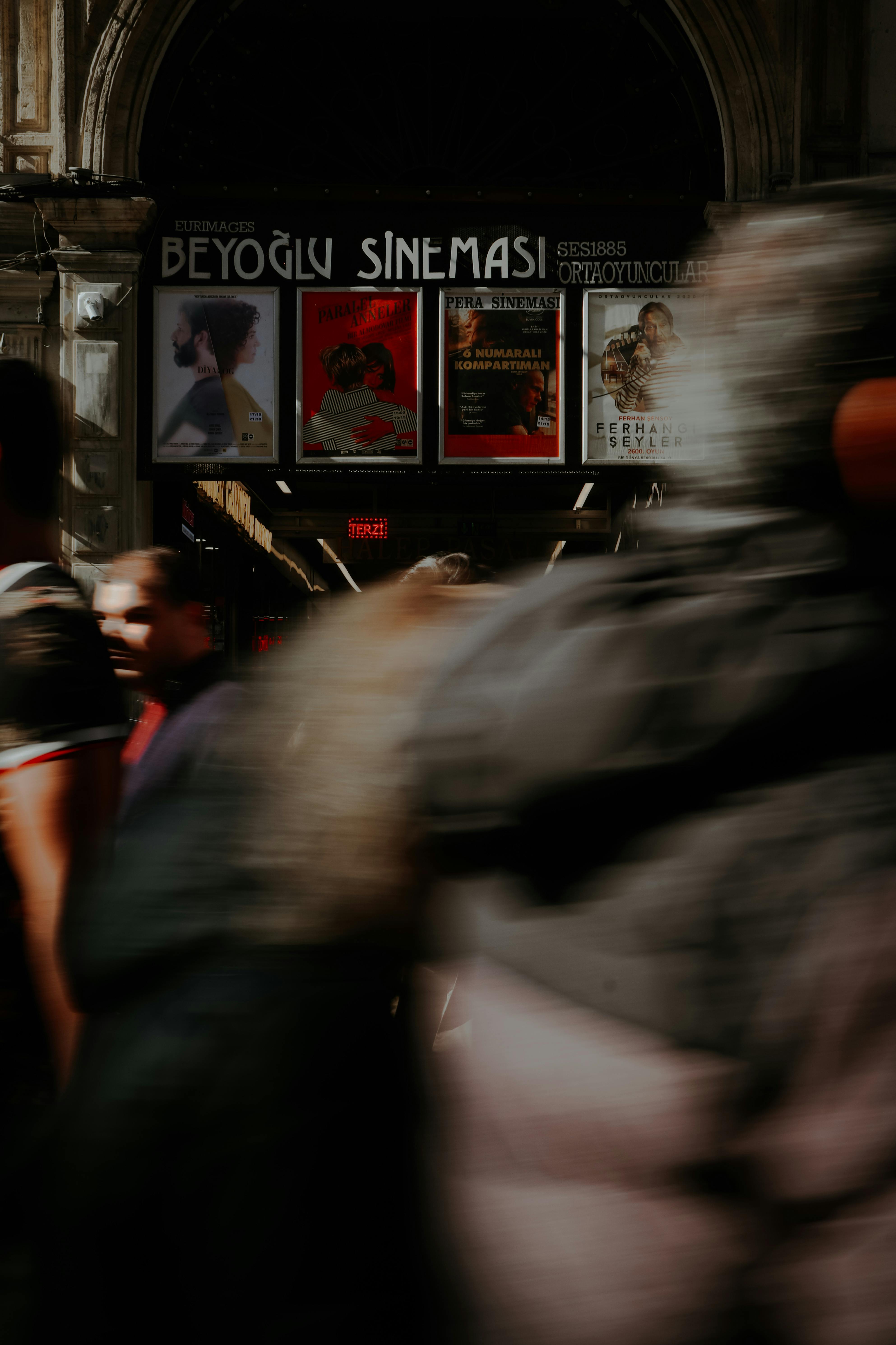 Blurred motion of people walking past Beyoglu Sinemasi entrance.