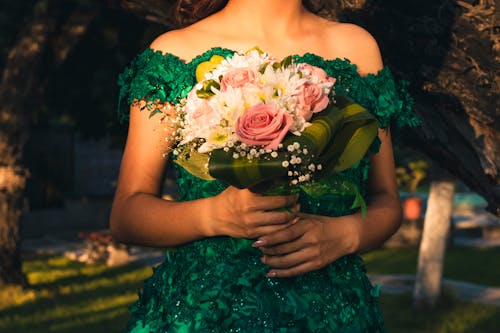 Free A Woman in Green Off Shoulder Dress Holding a Bouquet of Flowers Stock Photo