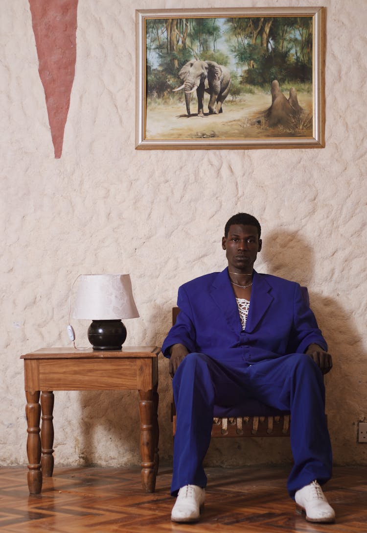 Man Sitting On Armchair Under Painting