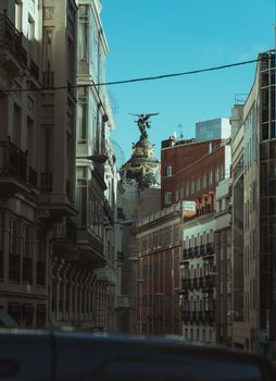 View of historic building facades in a European city with a prominent statue.