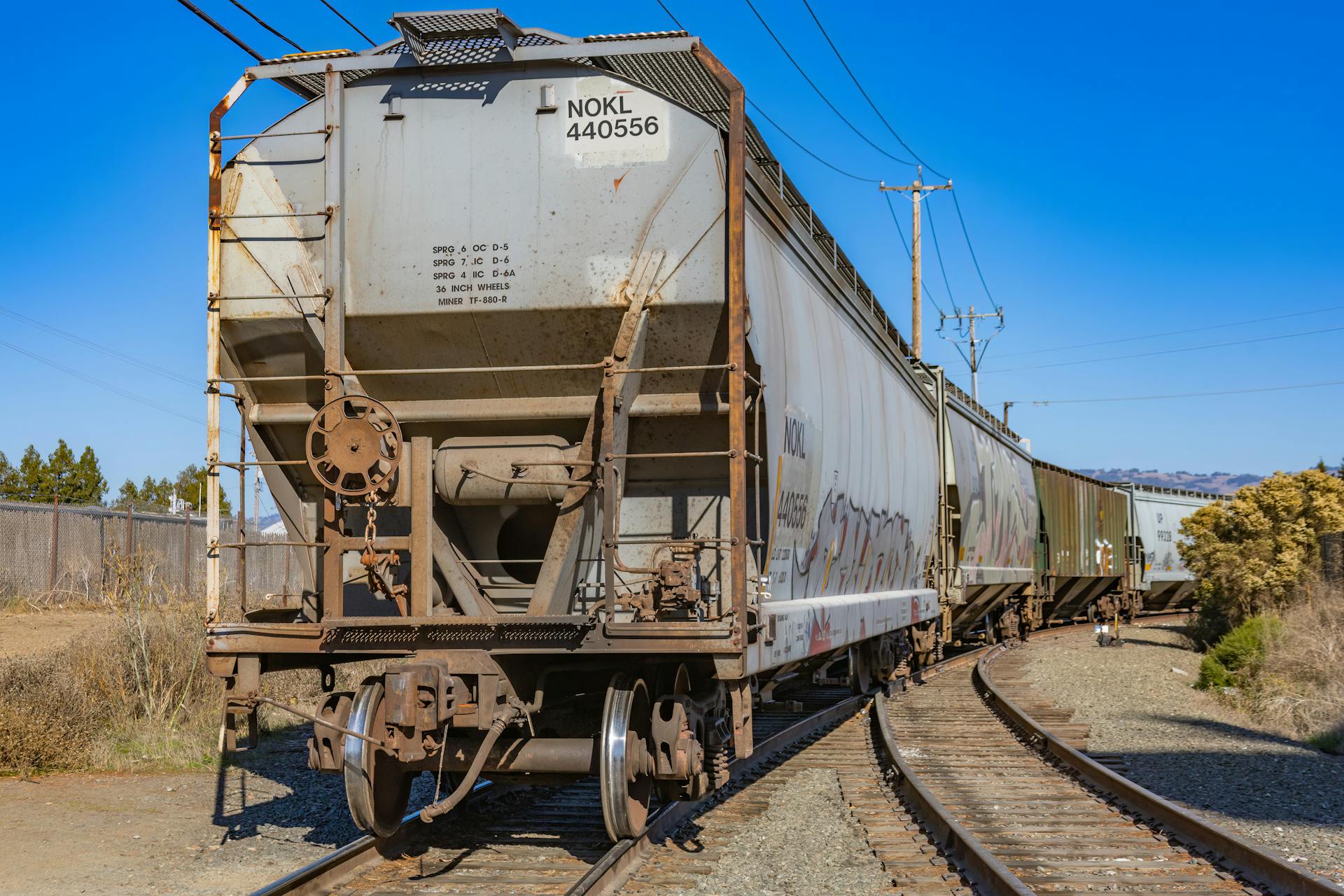A cargo train moves along curved railroad tracks under a clear blue sky, showcasing modern logistics.