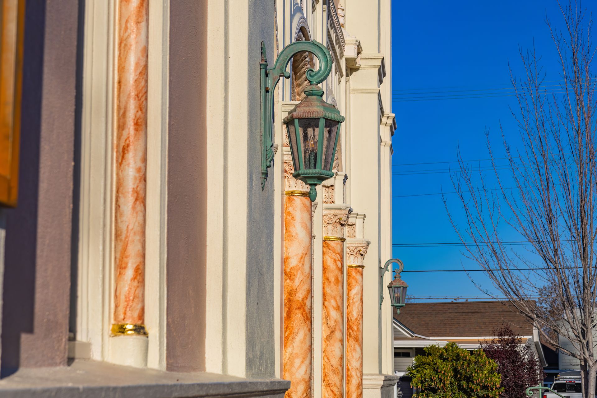 Elegant facade with ornate columns and vintage lanterns under a clear blue sky.