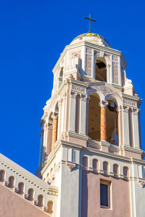 Free Elegant church tower with intricate architecture and cross under clear blue sky. Stock Photo