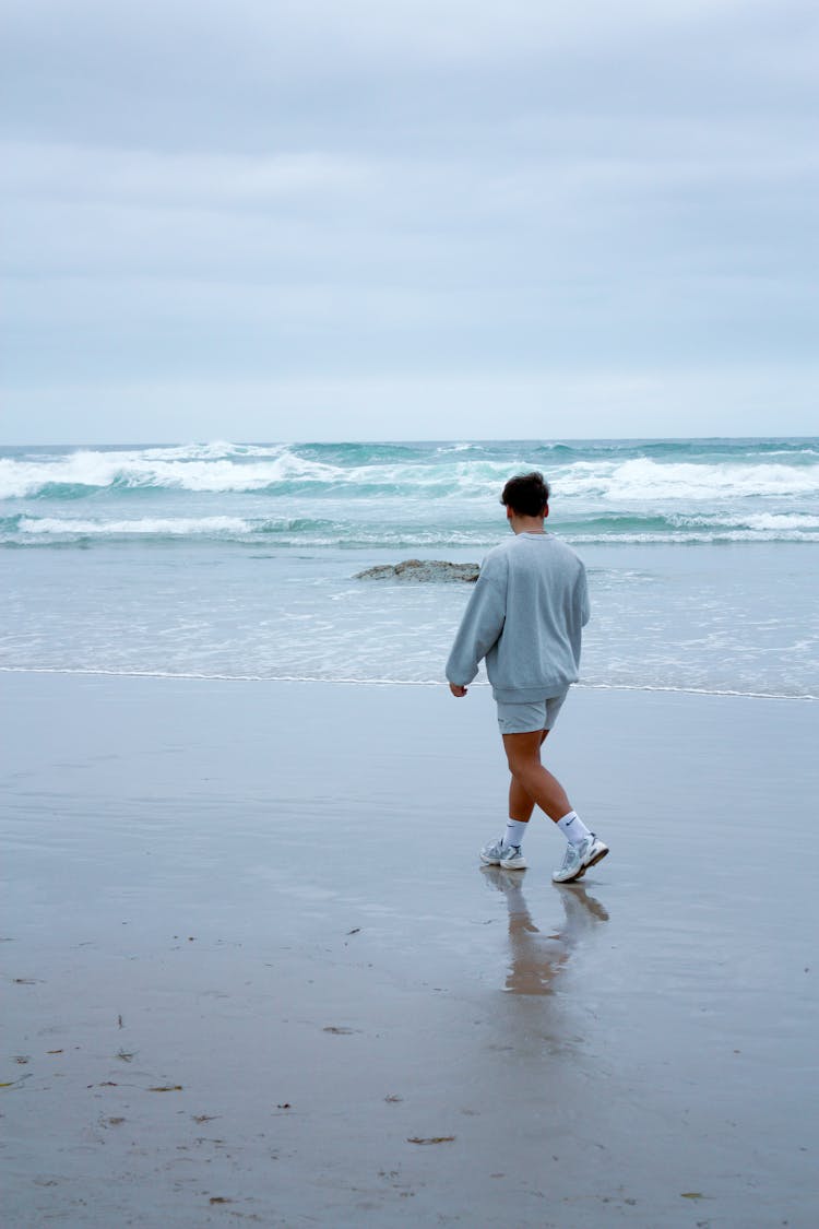 Young Man Walking On The Beach 