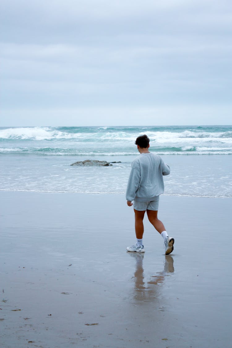 Young Man Walking On The Beach 