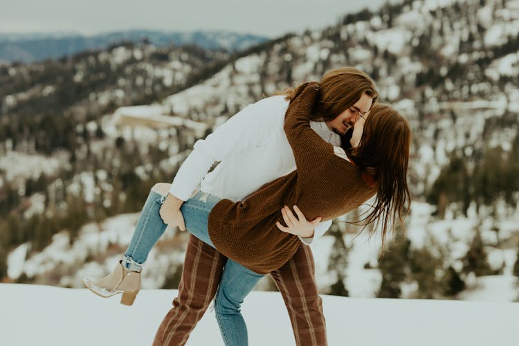 A Couple On The Snow Covered Mountain Hugging