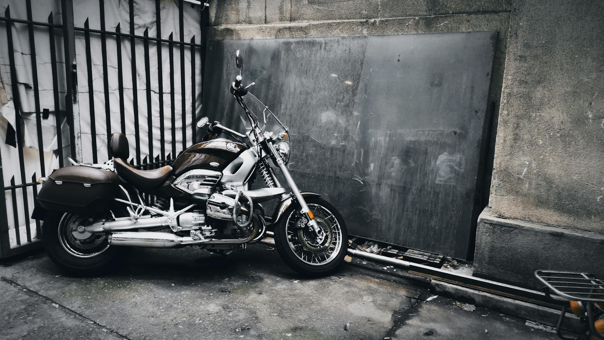 A classic cruiser motorcycle parked near an urban gate in Belgrade, Serbia's cityscape.