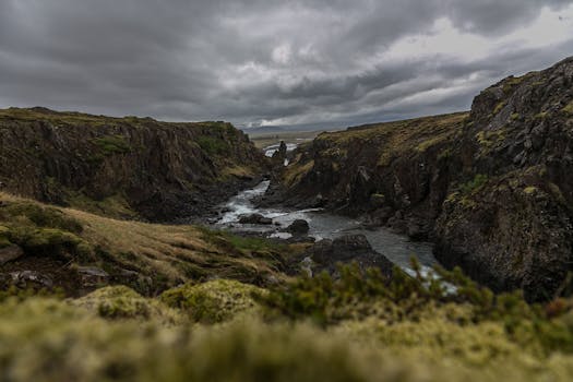 Explore the breathtaking Icelandic landscape featuring a rugged river valley under dramatic cloudy skies.
