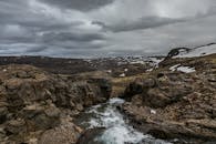在多云的天空下，落基山脉的戏剧性景观中，河流流动，积雪覆盖