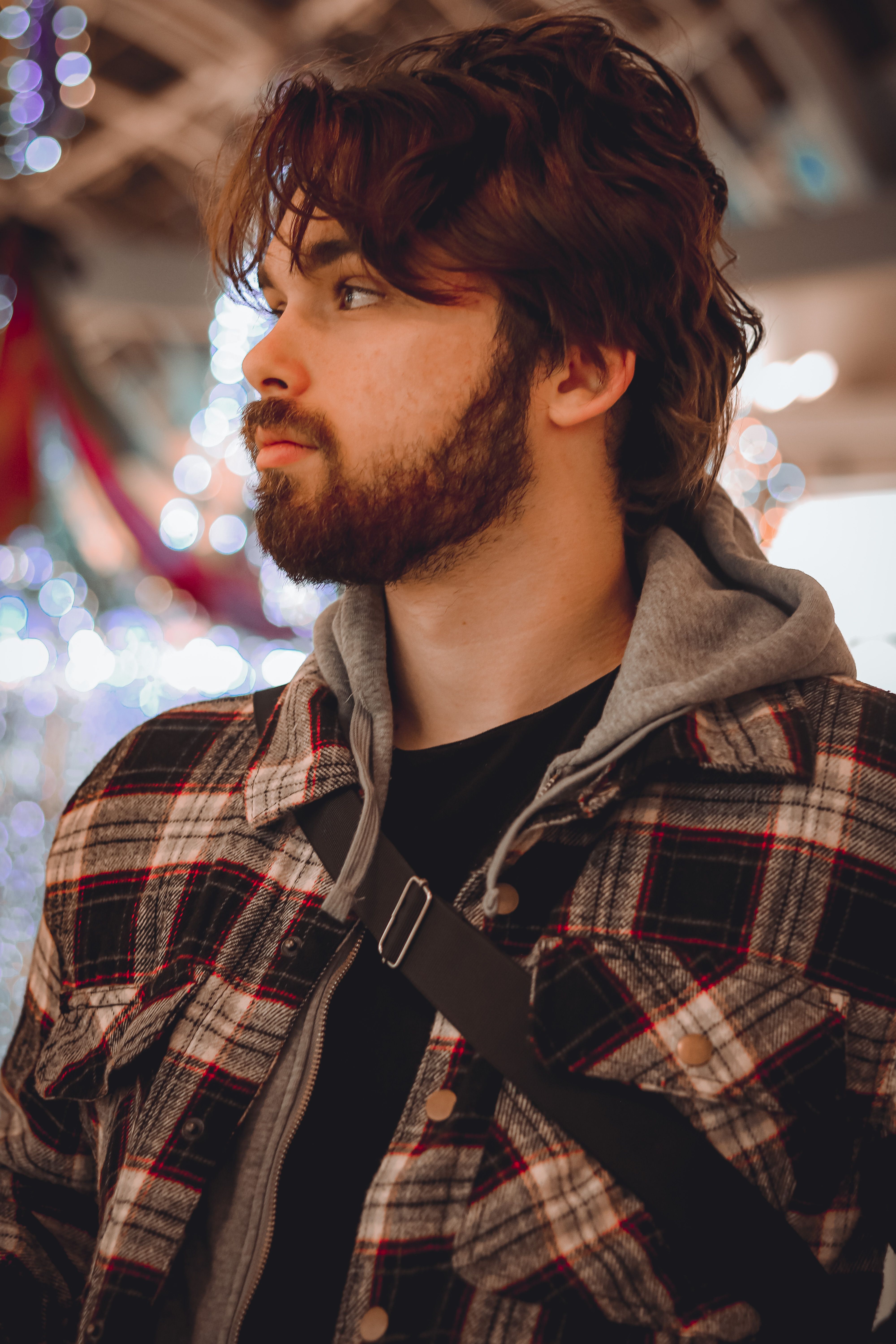 Portrait of a young bearded man in casual wear looking away indoors.
