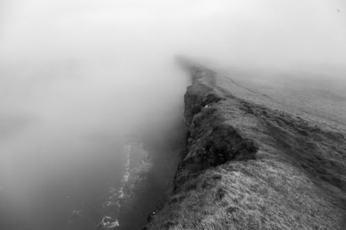 Grayscale Photo of Cliff Near Body of Water