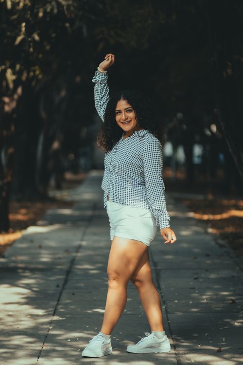 Free A confident woman posing on a sunlit path, embracing body positivity in a summer outfit. Stock Photo