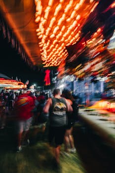 Dynamic blurred image capturing a bustling city carnival at night, filled with neon lights and people.