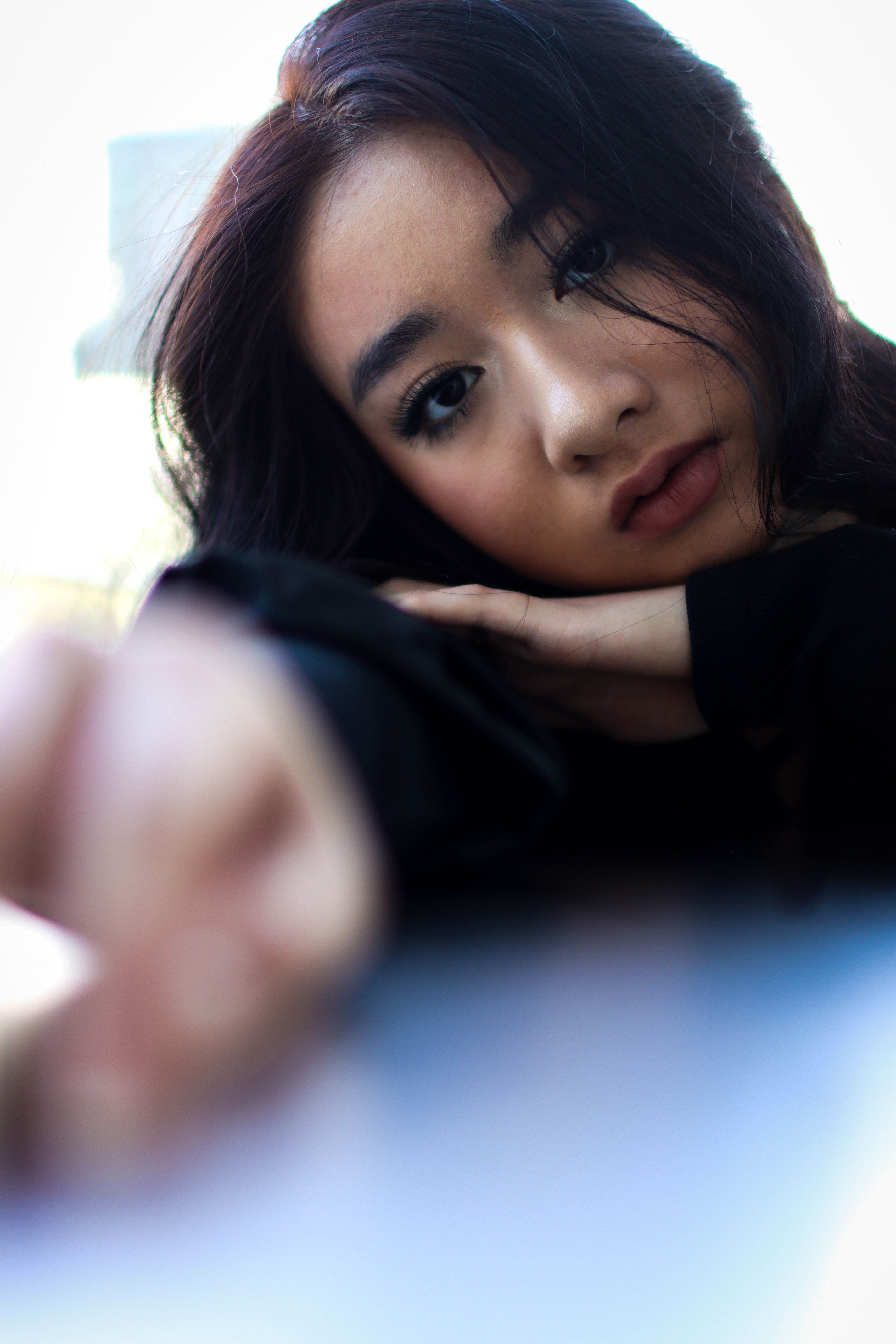 Close-up of an Asian woman with a thoughtful, introspective gaze, captured in a soft-focus artistic portrait.