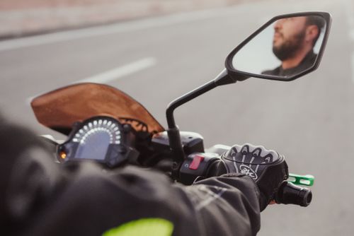 Free Motorcyclist riding on a road, focusing on handlebar and mirror reflections. Stock Photo