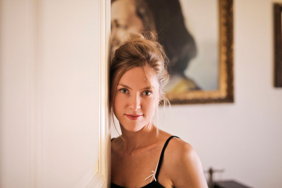 Portrait of a young woman posing indoors with art in the background.