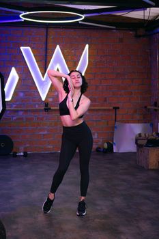 A young woman in activewear stretching in a modern gym setting.
