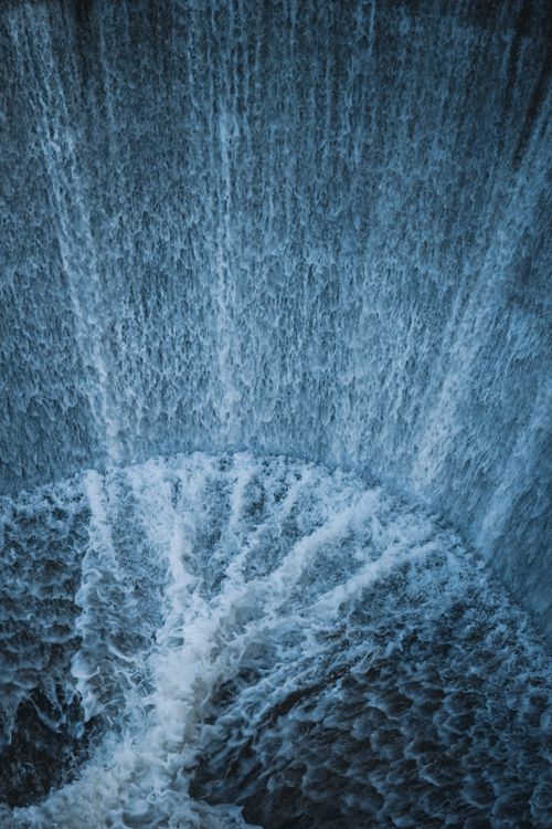 Free Captivating aerial view of a powerful waterfall cascading into a swirling pool. Stock Photo