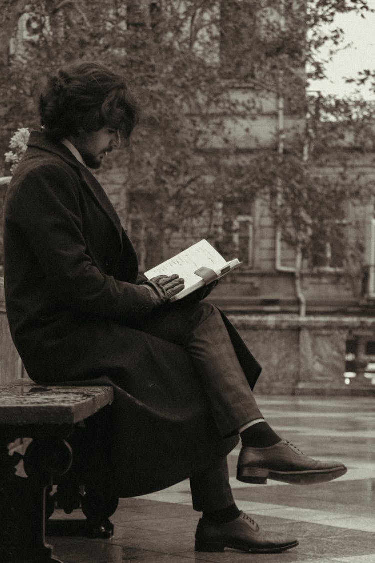 Man Sitting On The Concrete Bench Reading A Book 