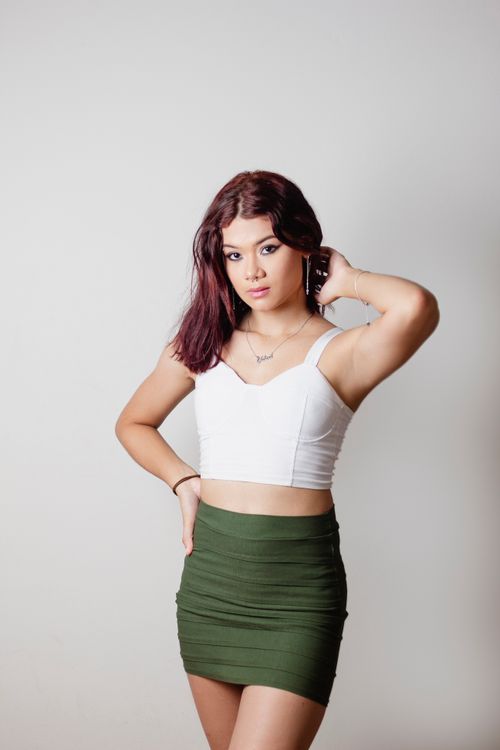 Free Fashionable young woman posing in studio wearing trendy outfit on white background. Stock Photo