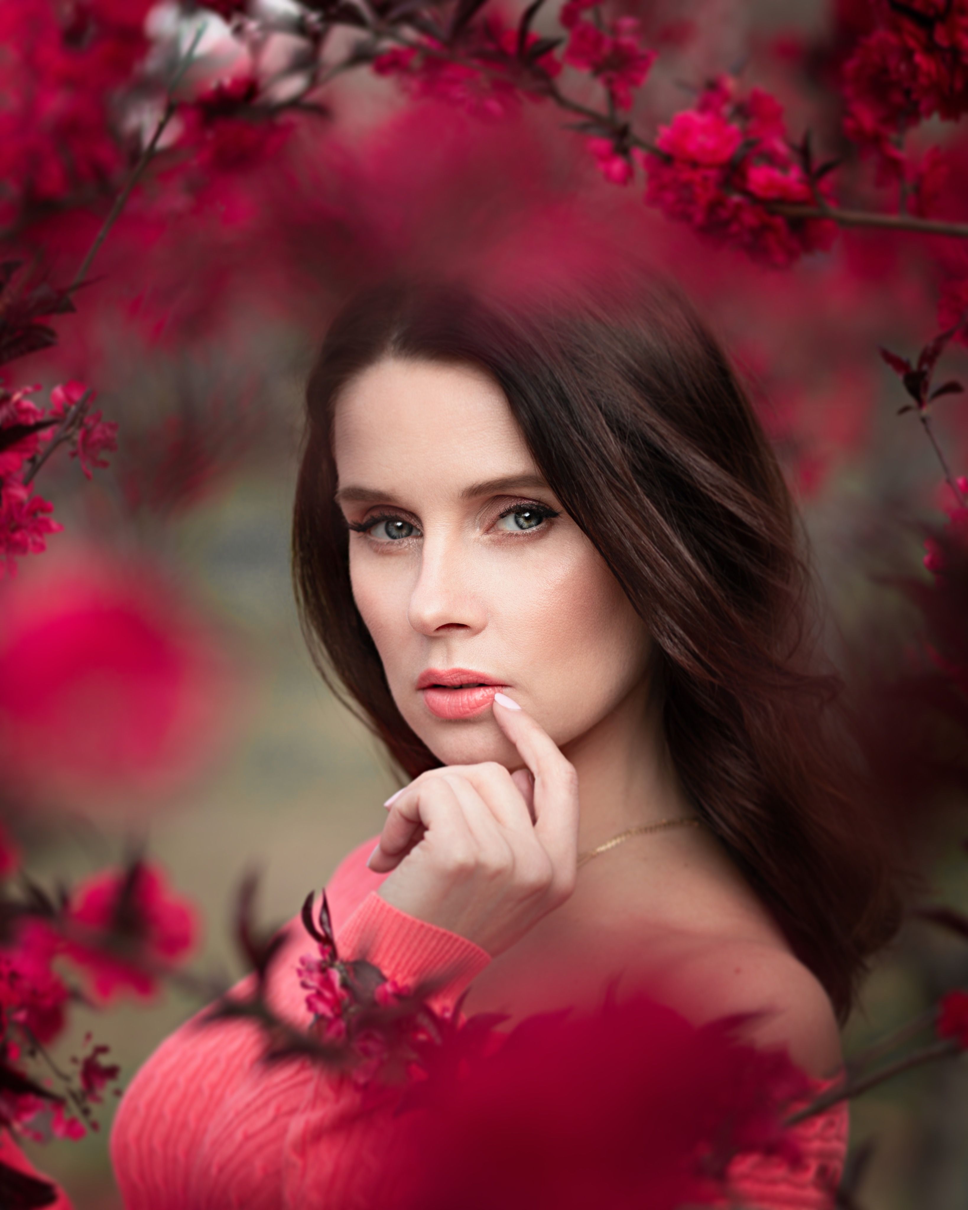 Portrait of a stylish woman in red roses, capturing beauty and elegance outdoors.