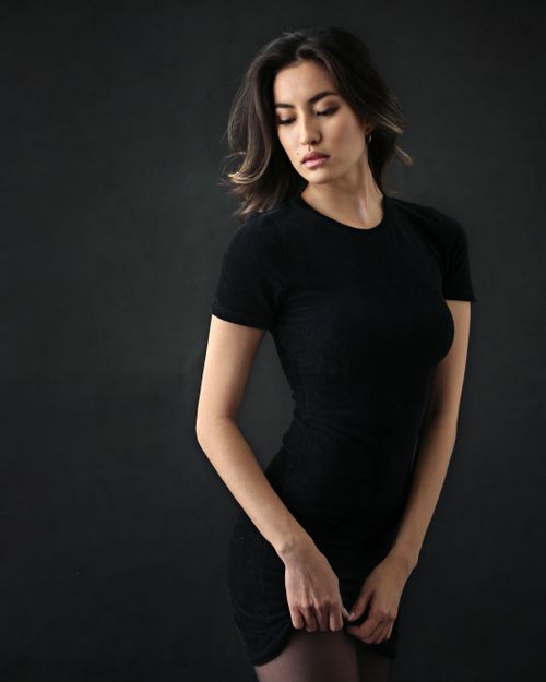 Free Chic studio portrait of a woman in a black dress with a moody background. Stock Photo