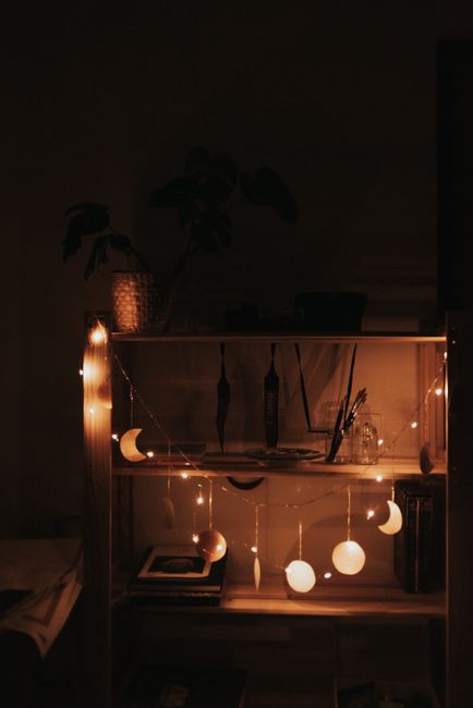 Warm and inviting shelf decor featuring illuminated string lights and crescent moon ornaments for a cozy ambiance.
