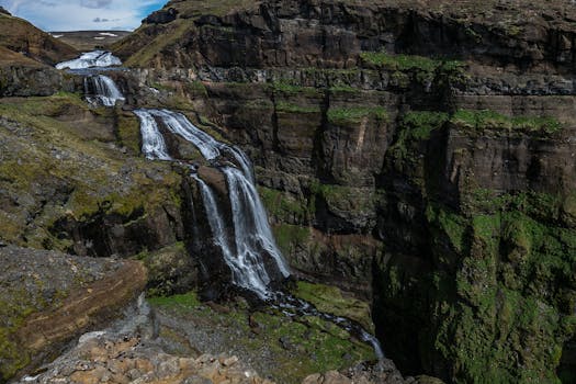 瀑布顺着郁郁葱葱的绿色环绕的岩石峡谷悬崖倾泻而下，景象令人叹为观止