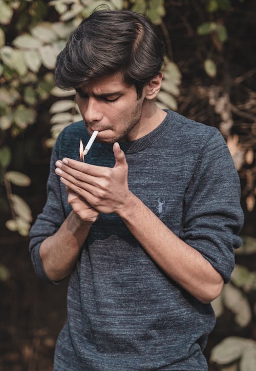 A Man in Gray Sweater Smoking Cigarette