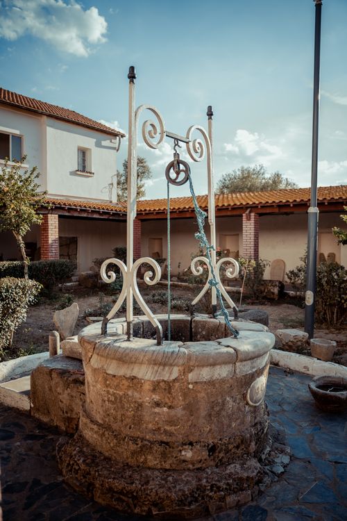 Free A picturesque stone wishing well in a serene Annaba courtyard under a clear blue sky. Stock Photo