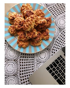 俯视桌上花边旁的自制饼干装饰板，位于笔记本电脑一侧